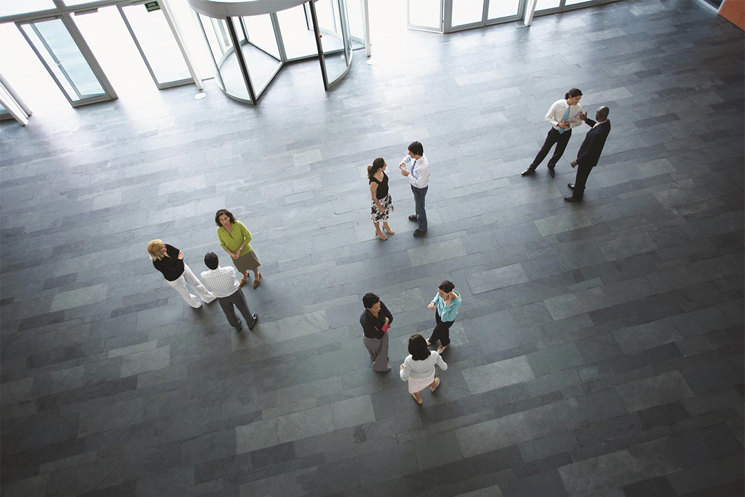 Geschäftsleute stehen in kleinen Gruppen in einer Eingangshalle zusammen und unterhalten sich